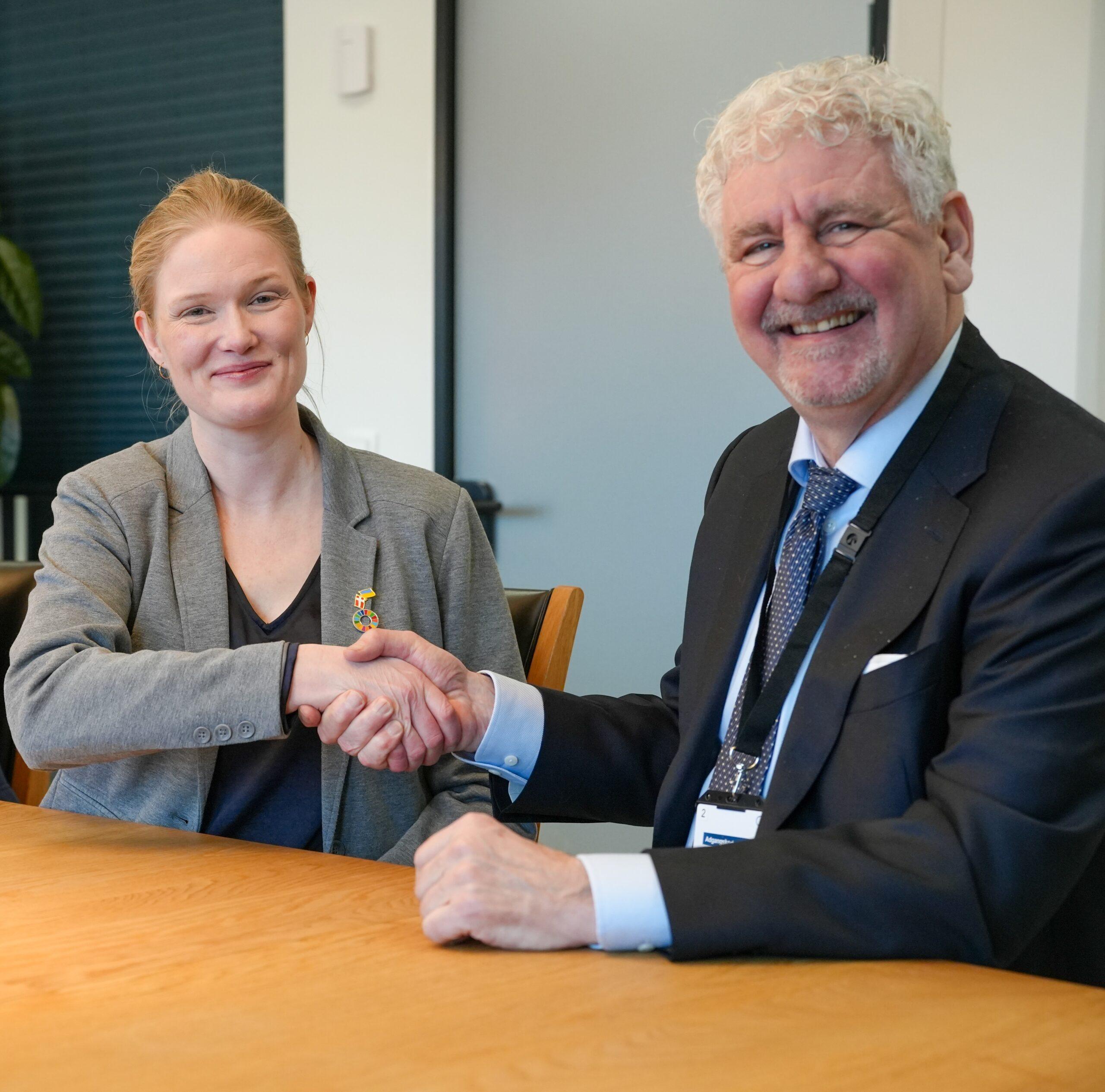 Two people shaking hands at a signing ceremony